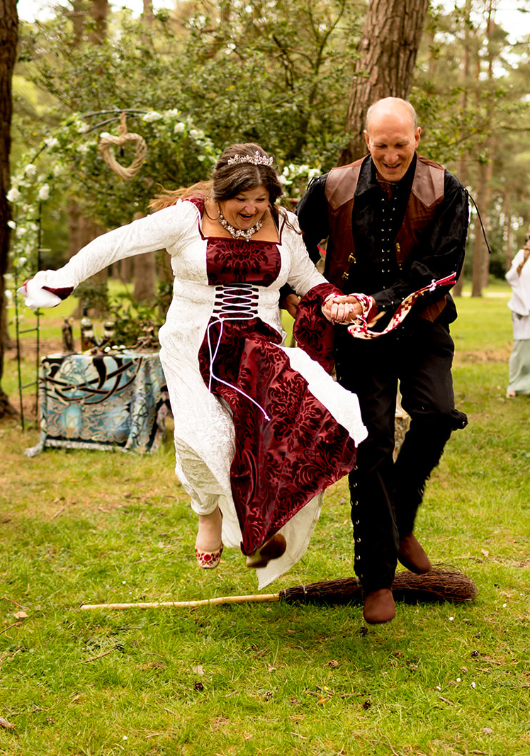 Just married couple jumping over broomstick