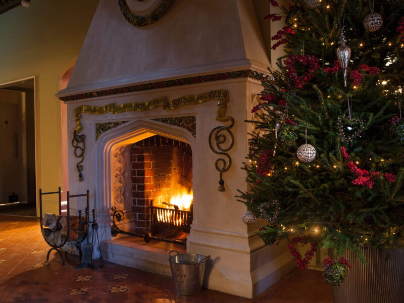 Cosy Christmas fireplace at Burley Manor, complete with roaring fire, twinkling fairy lights, and traditional festive décor—capturing the warmth and charm of a New Forest winter retreat